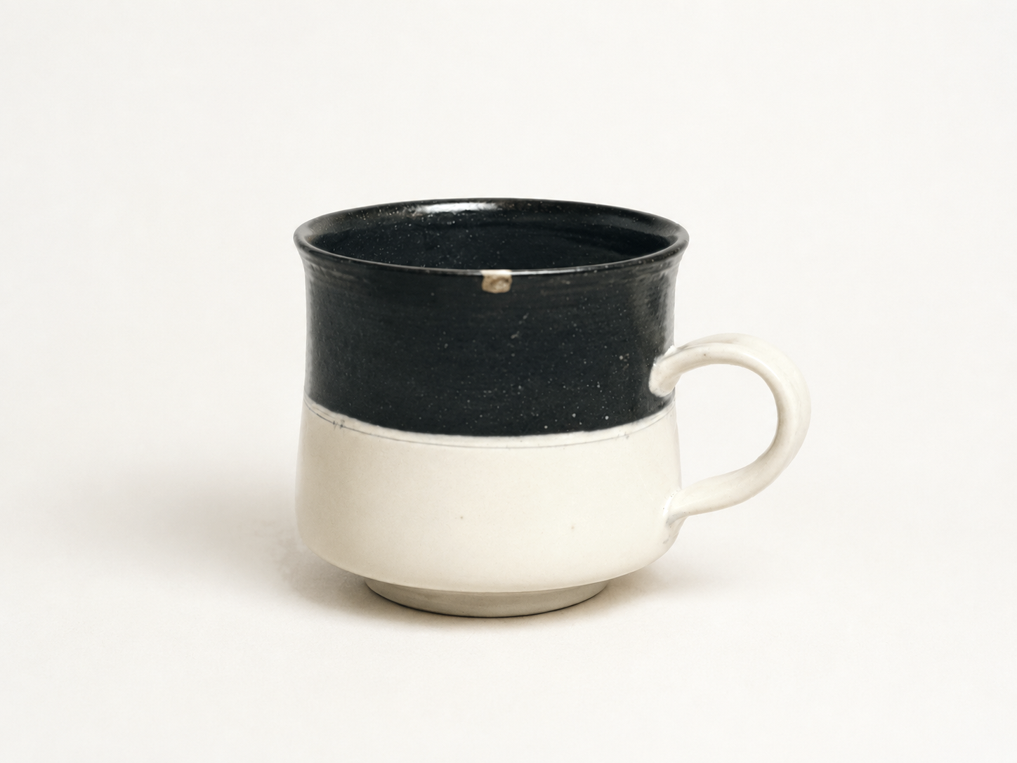 白とこげ茶のカップ。口縁の欠けを本漆金継ぎで繕う（Atelier KYM）